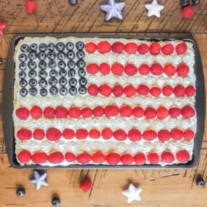 Cookie bar topped with frosting, raspberries and blueberries arranged to look like an American flag.