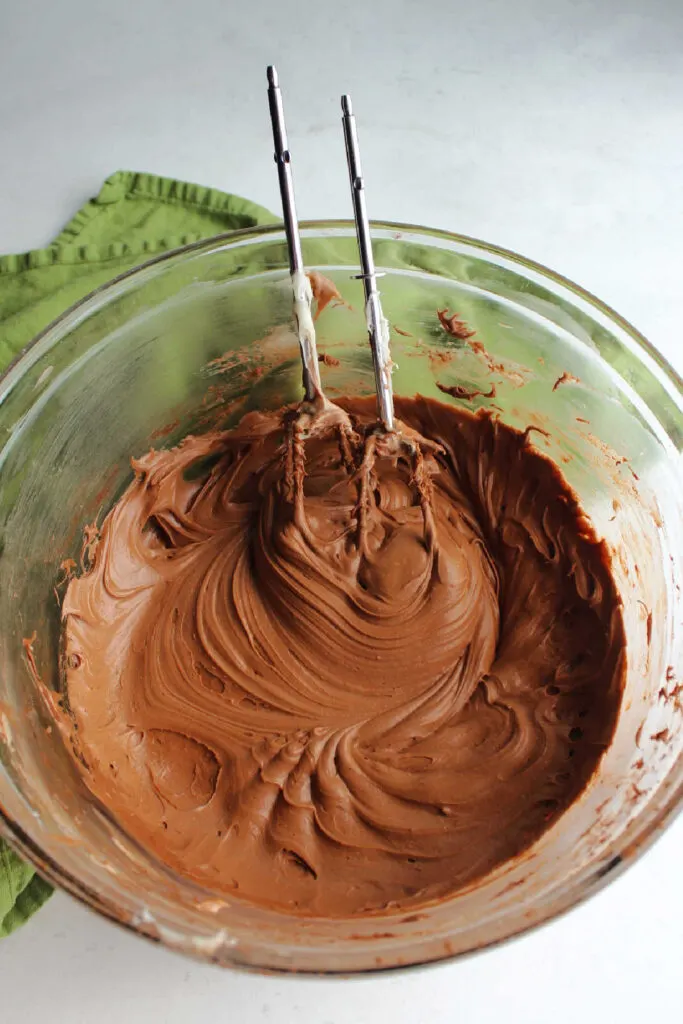 Mixing bowl filled with smooth chocolate cream cheese frosting.