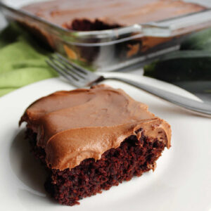 Piece of chocolate zucchini cake topped with smooth creamy chocolate cream cheese frosting.