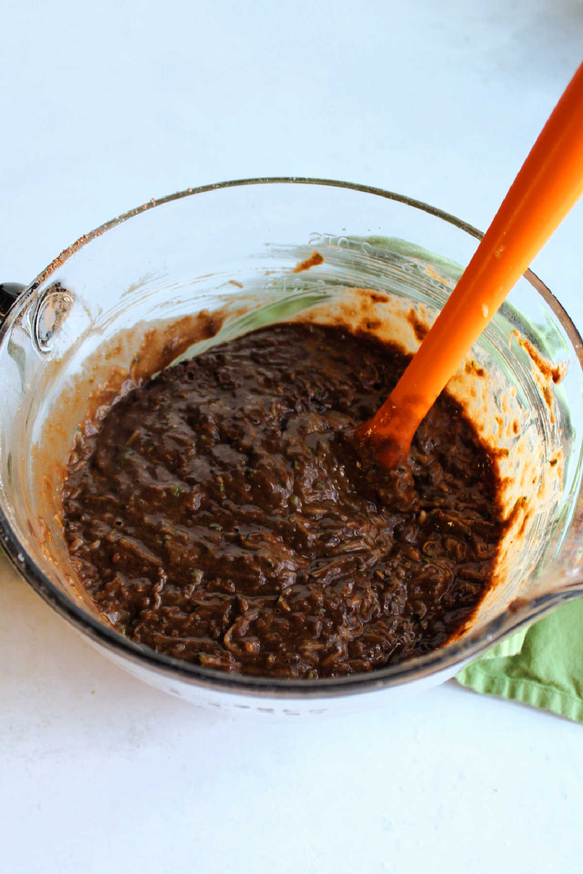 Bowl of chocolate cake batter with shredded zucchini inside.