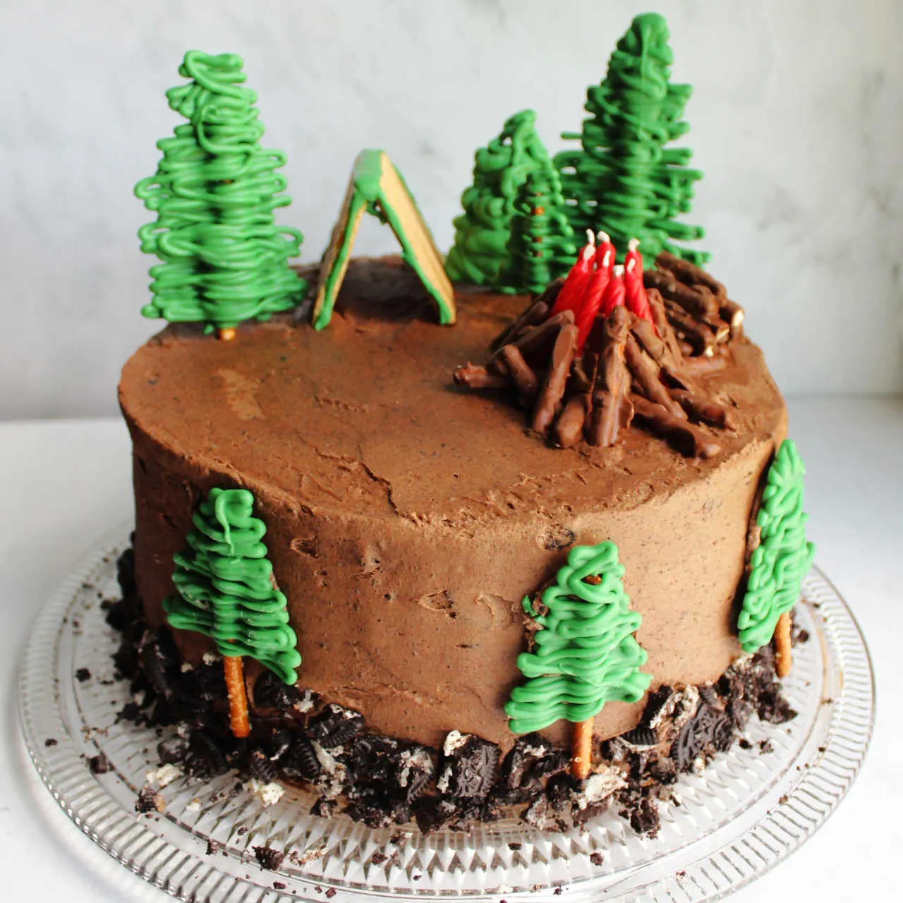 Camping cake with pretzel trees, a campfire candle arrangement and tent.