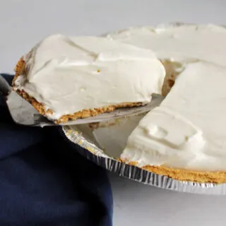 Lifting a slice of creamy lemon pie out of the pie pan.
