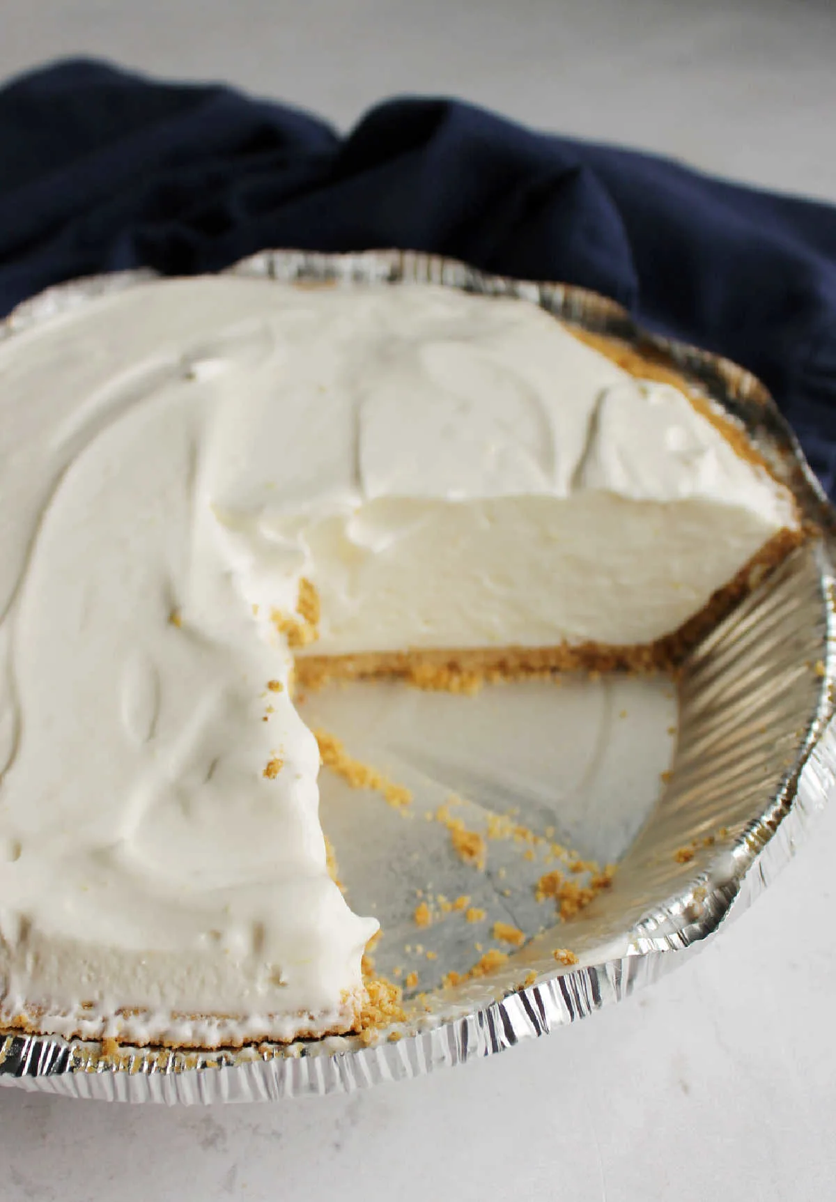 Creamy lemon pie in plate, missing a couple of slices showing the smooth lemon filling.