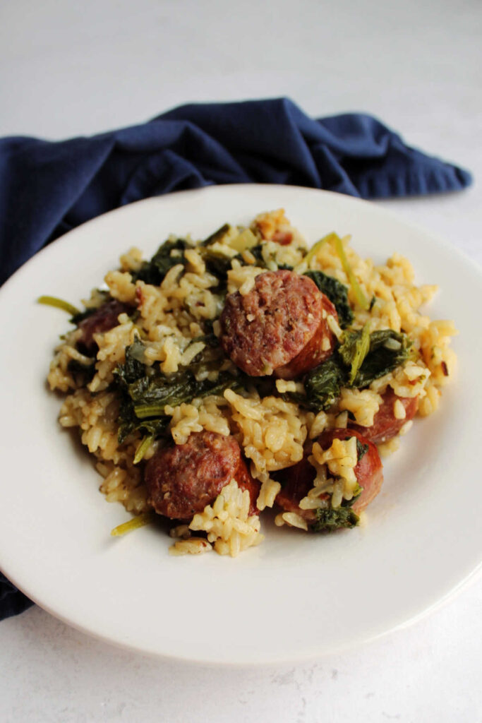 Dinner plate filled with rice, mustard greens and kielbasa ready to eat.