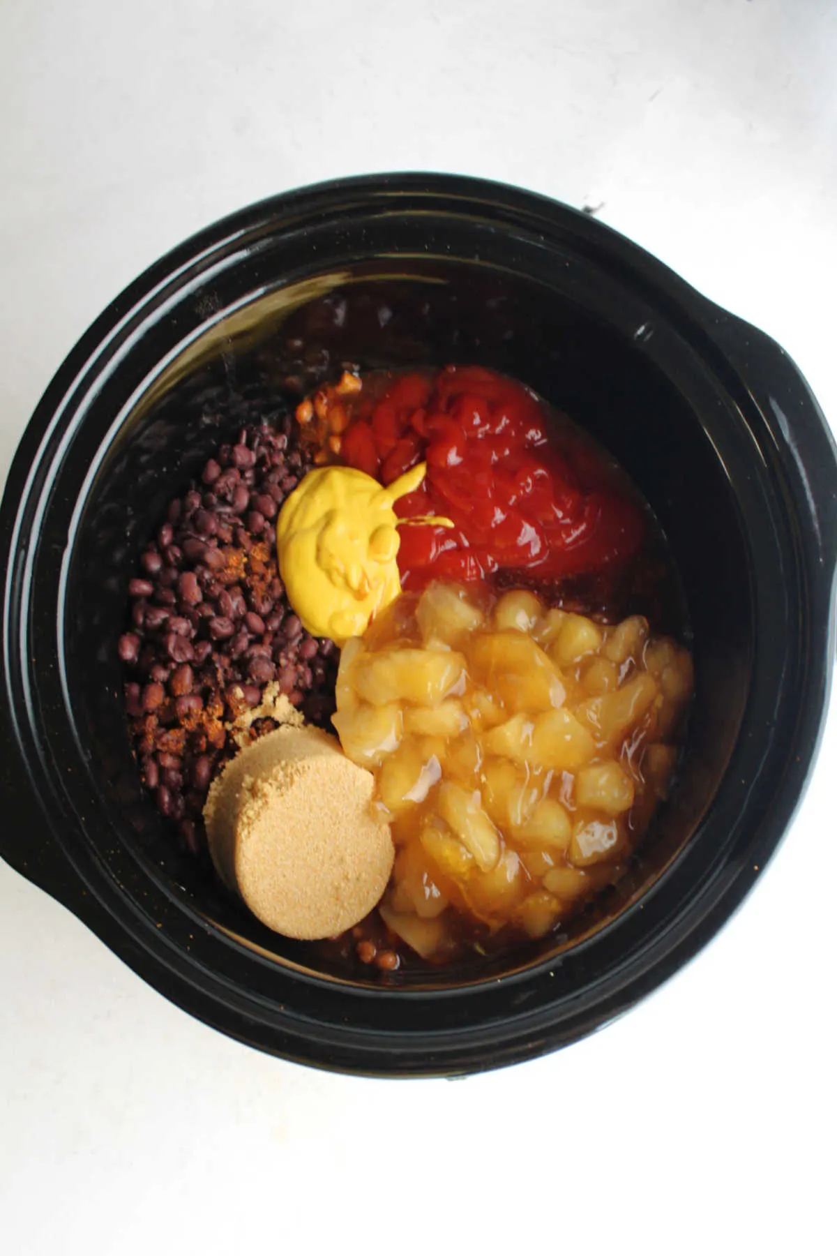 Beans, ketchup, mustard, brown sugar and apple pie filling in crockpot.
