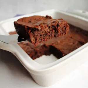 Lifting a super fudgy condensed milk brownie out of the pan.