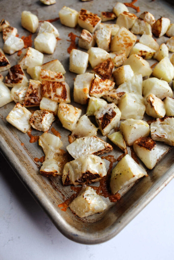 Parmesan cheese melted over roasted kohlrabi cubes, ready to serve.