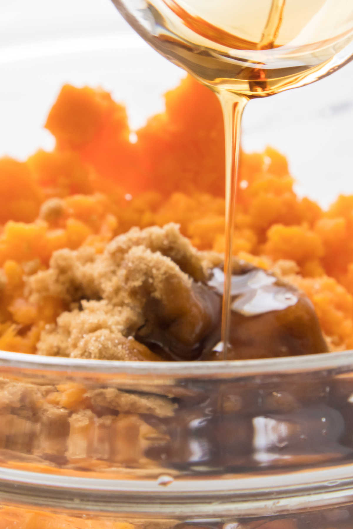 Pouring maple syrup into mashed sweet potatoes.