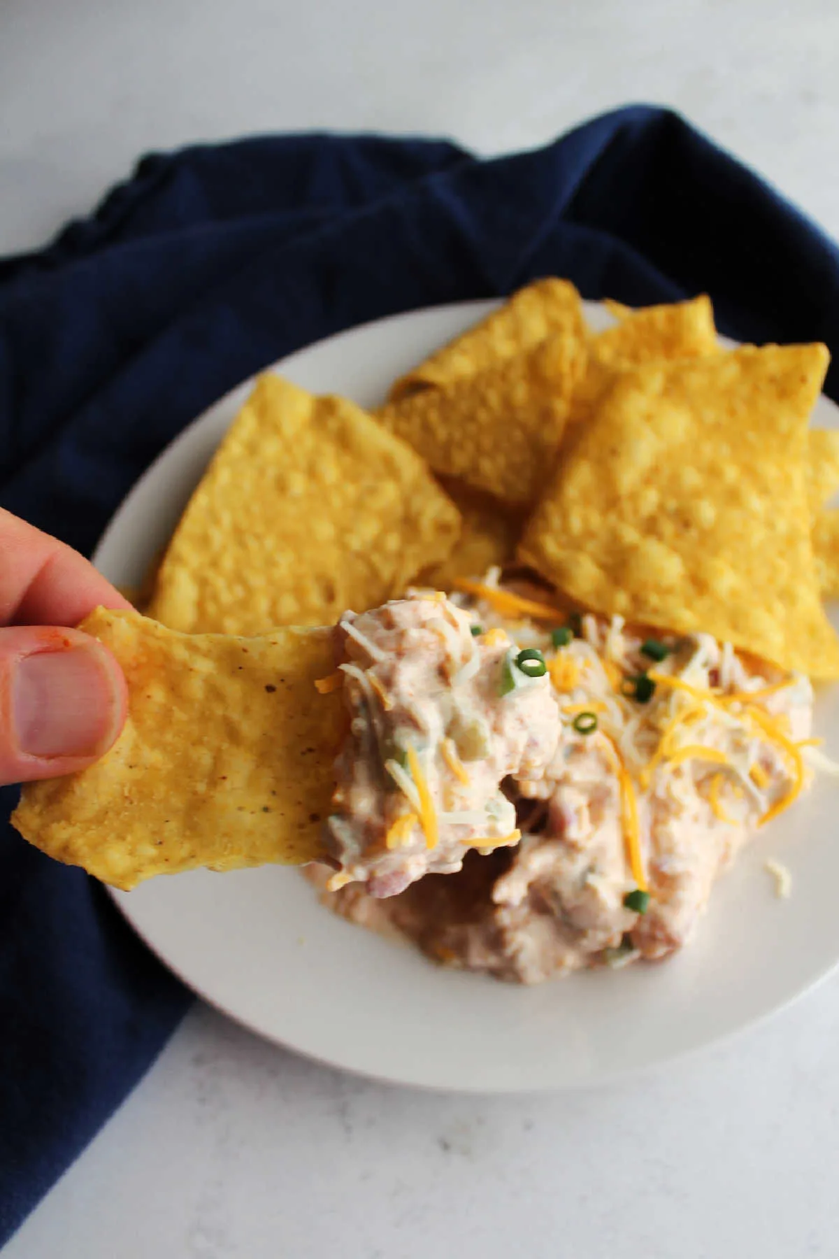 Hand dipping chip into cheesy sour cream dip.