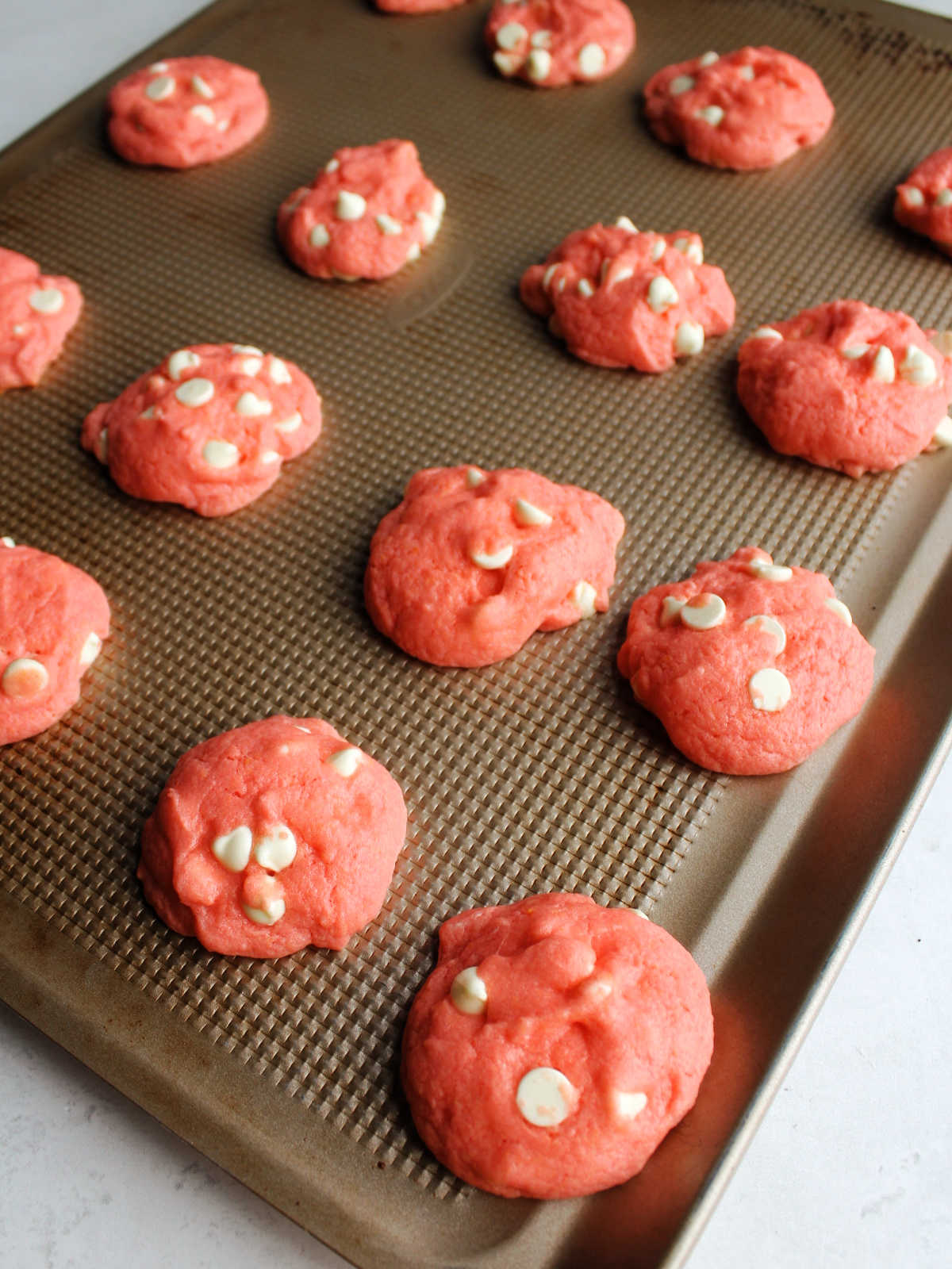 Fresh baked strawberry cookies on baking sheet.