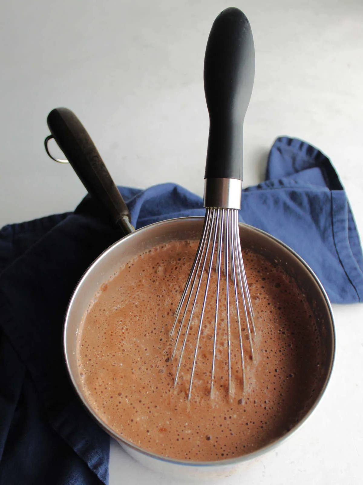 Milk and water whisked into the hot chocolate mix in saucepan.