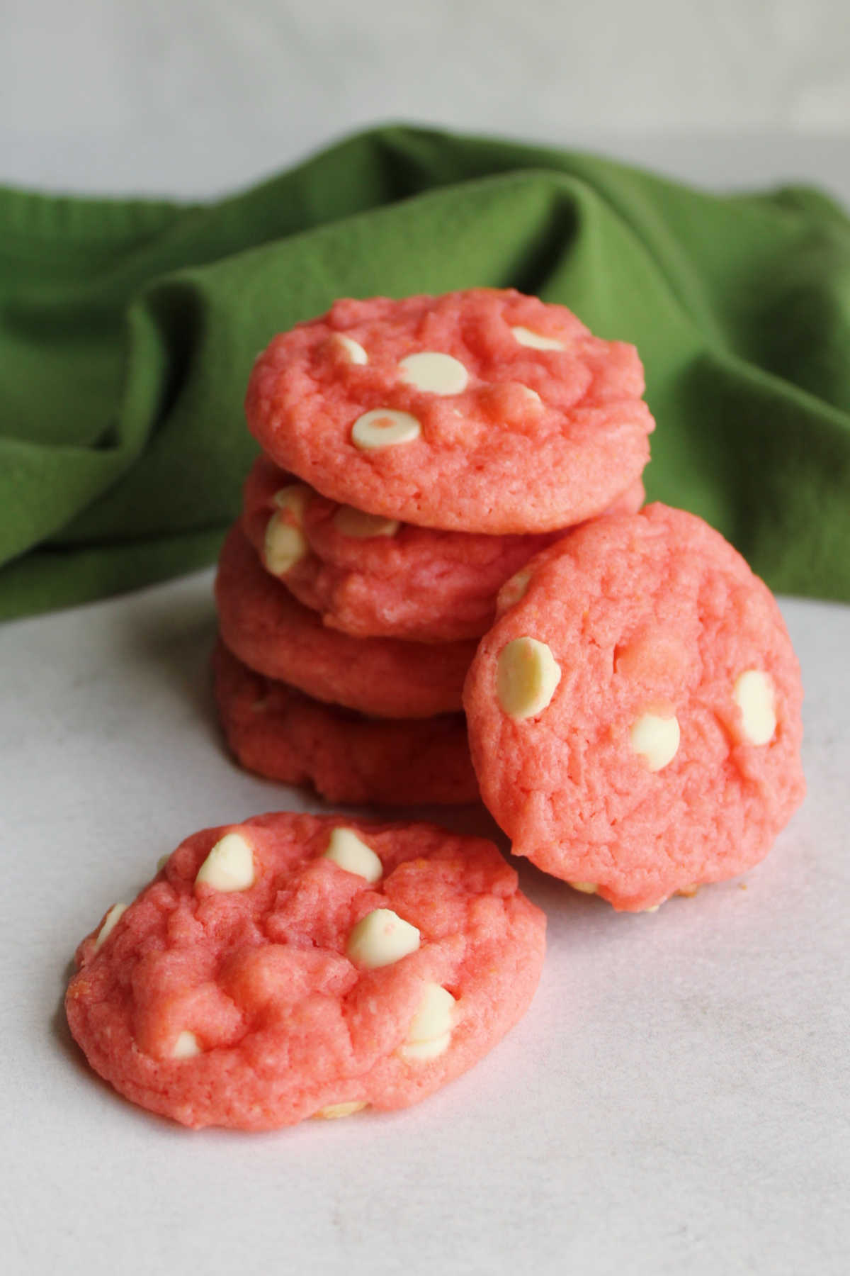 Several soft pink cookies with white chocolate chips.