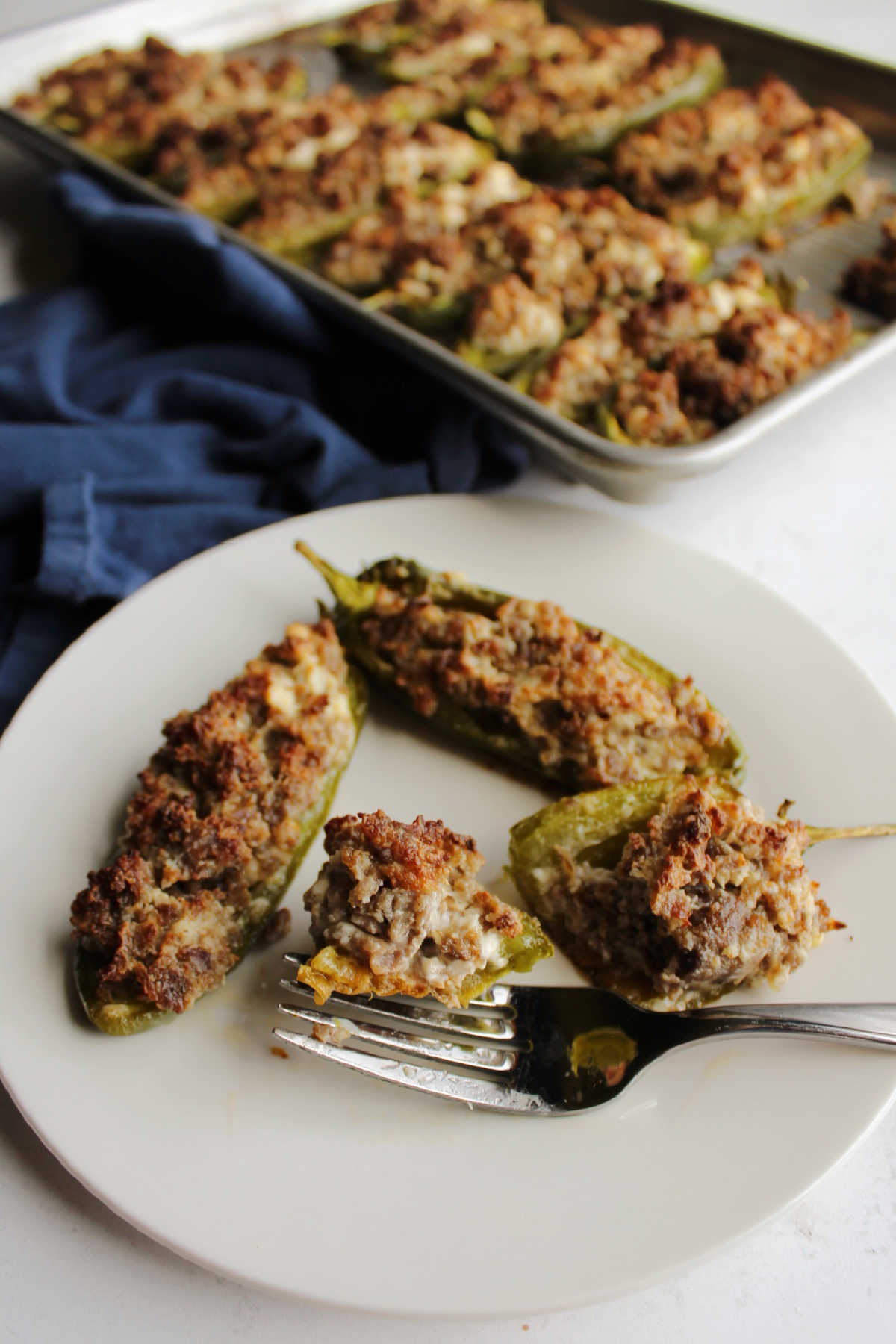 Bite of sausage and cream cheese stuffed jalapeno pepper on fork, ready to eat.