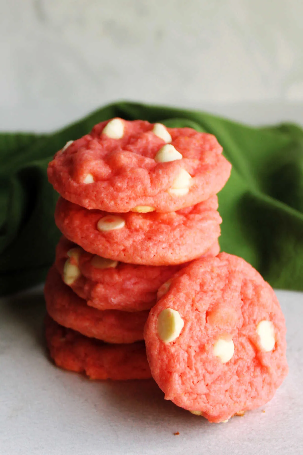 Strawberry cookie leaning against stack of cake mix cookies, ready to eat.