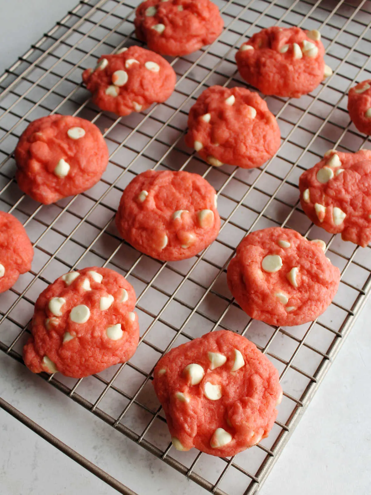 Pink strawberry cookies cooling on wire rack.