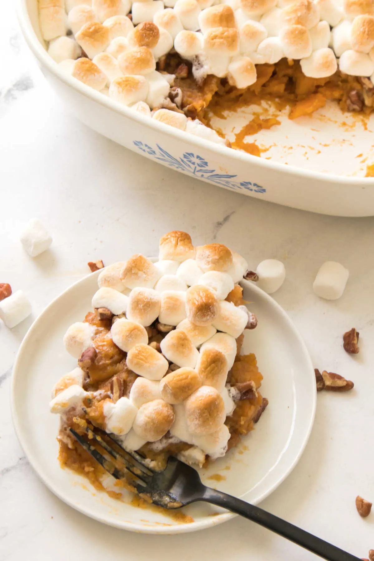 Serving of sweet potatoes topped with pecans and gooey marshmallows. 