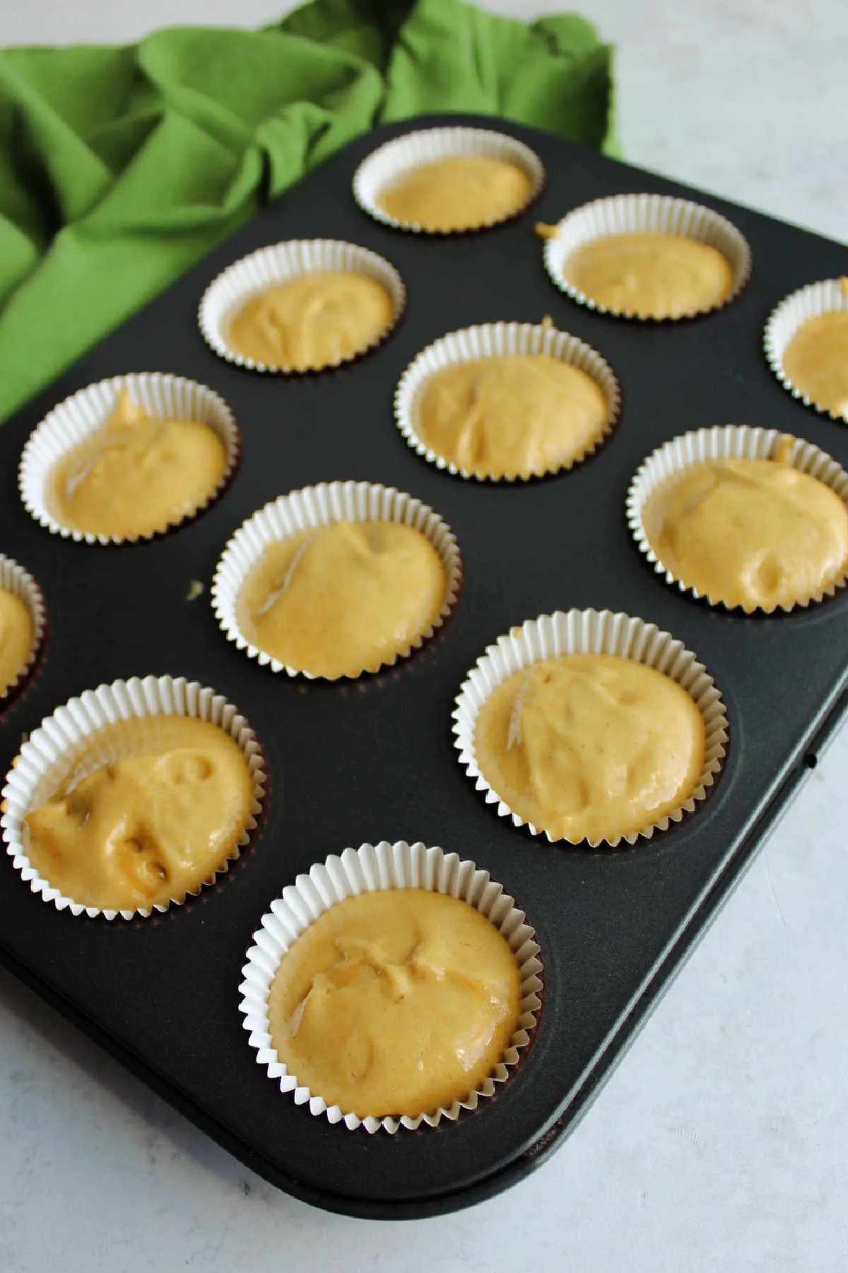 Apple butter cake batter scooped into paper lined mini cupcake tin.
