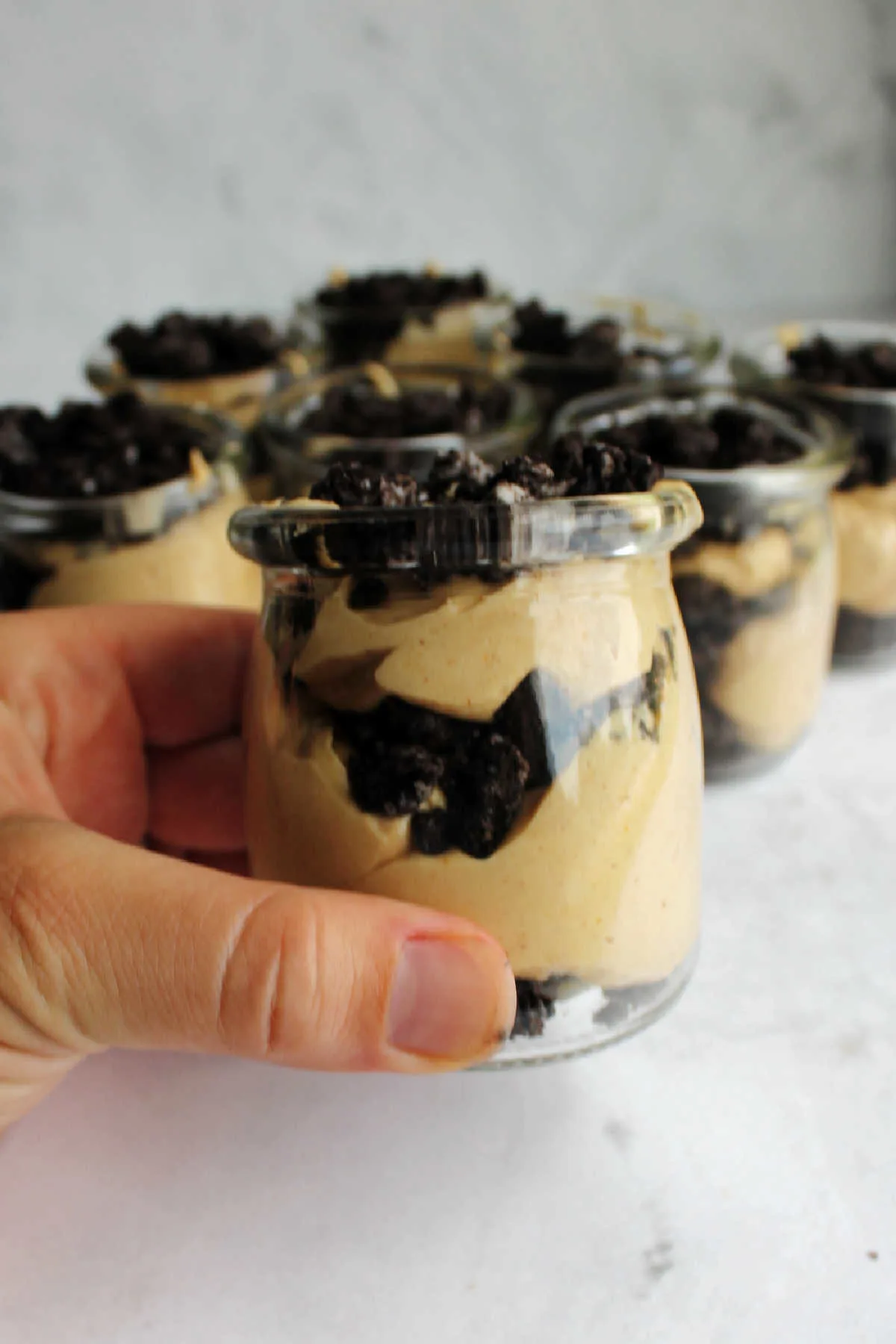Hand holding jar of peanut butter Oreo dirt pudding ready to eat.
