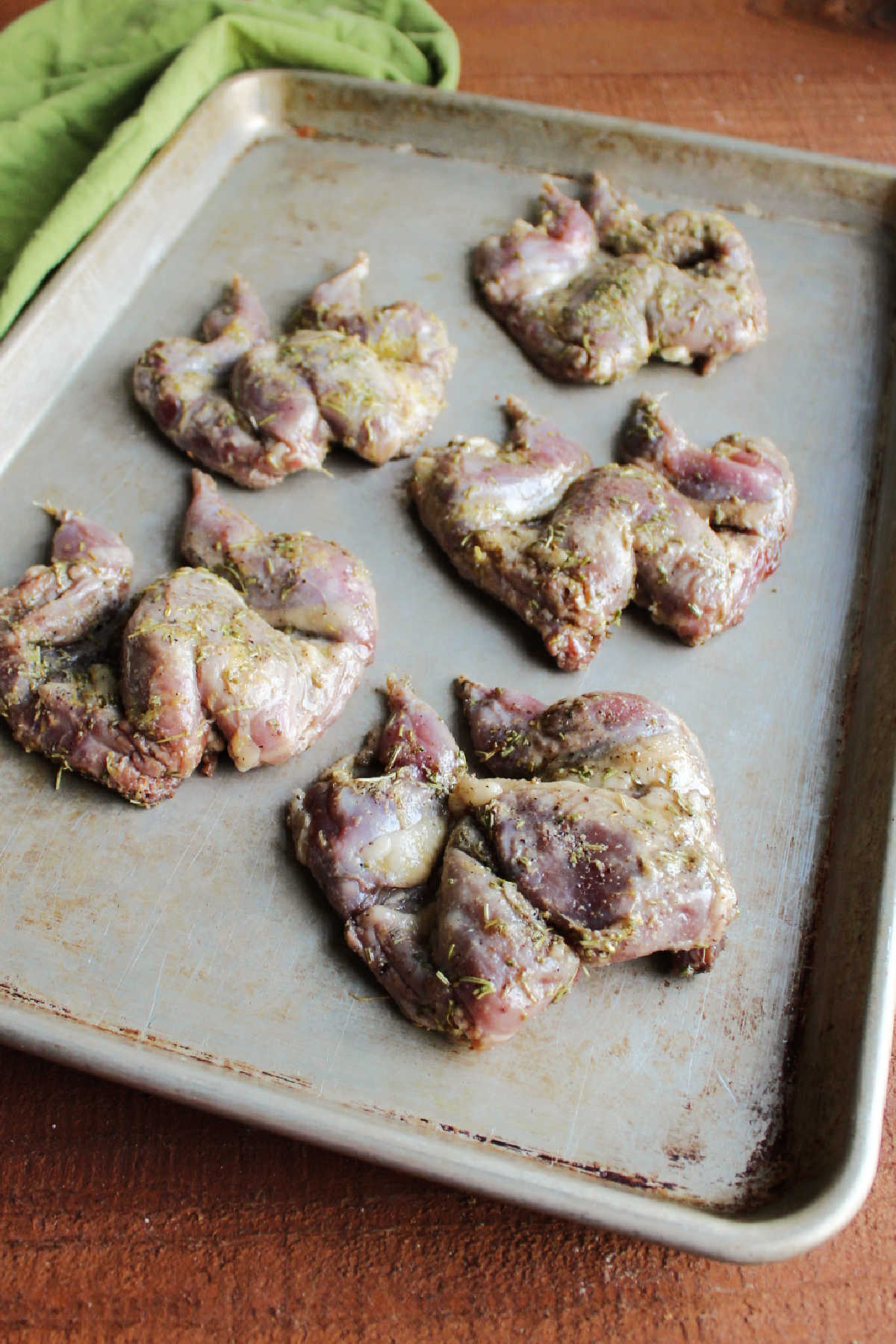 Spatchcocked quail spread out on sheet pan.