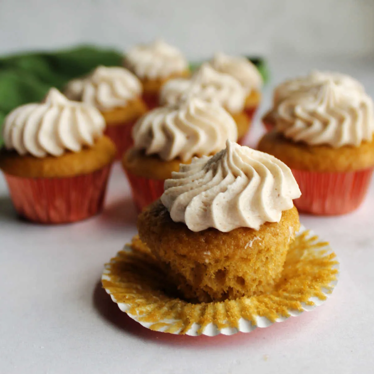 Apple butter mini cupcake unwrapped showing soft cake bottom topped with swirl of apple butter frosting.