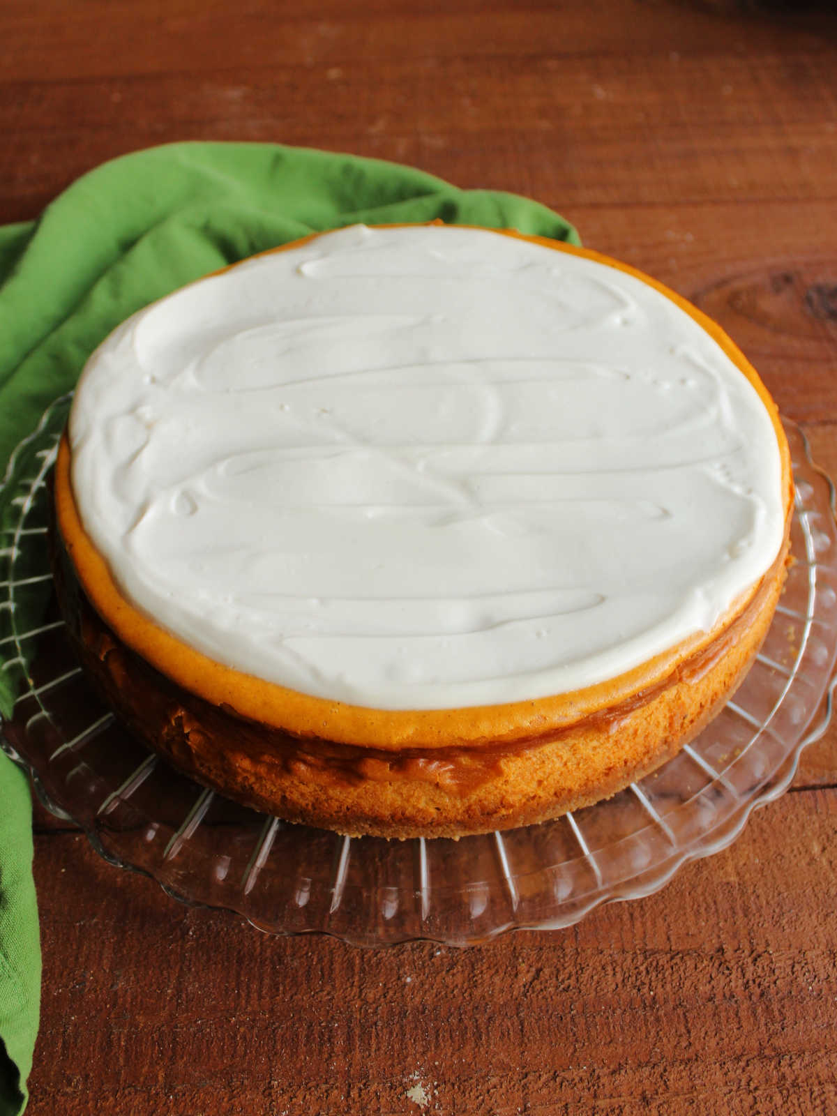 Whole pumpkin cheesecake with sour cream topping spread over the top.