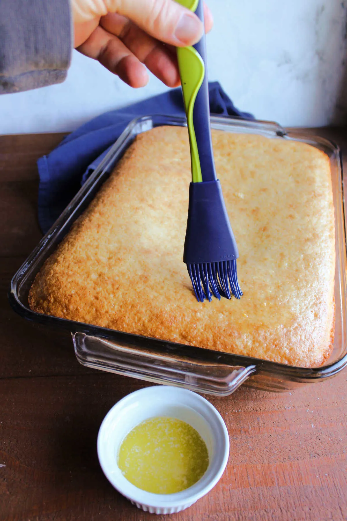 Brushing melted butter over golden brown topped cornbread fresh from the oven.