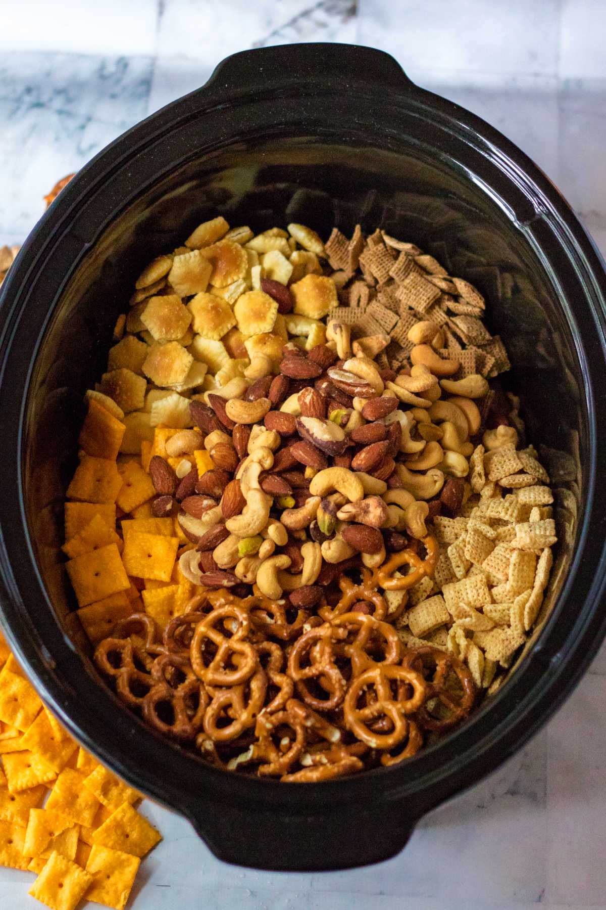 Slow cooker filled with crackers, cereal, nuts and more.