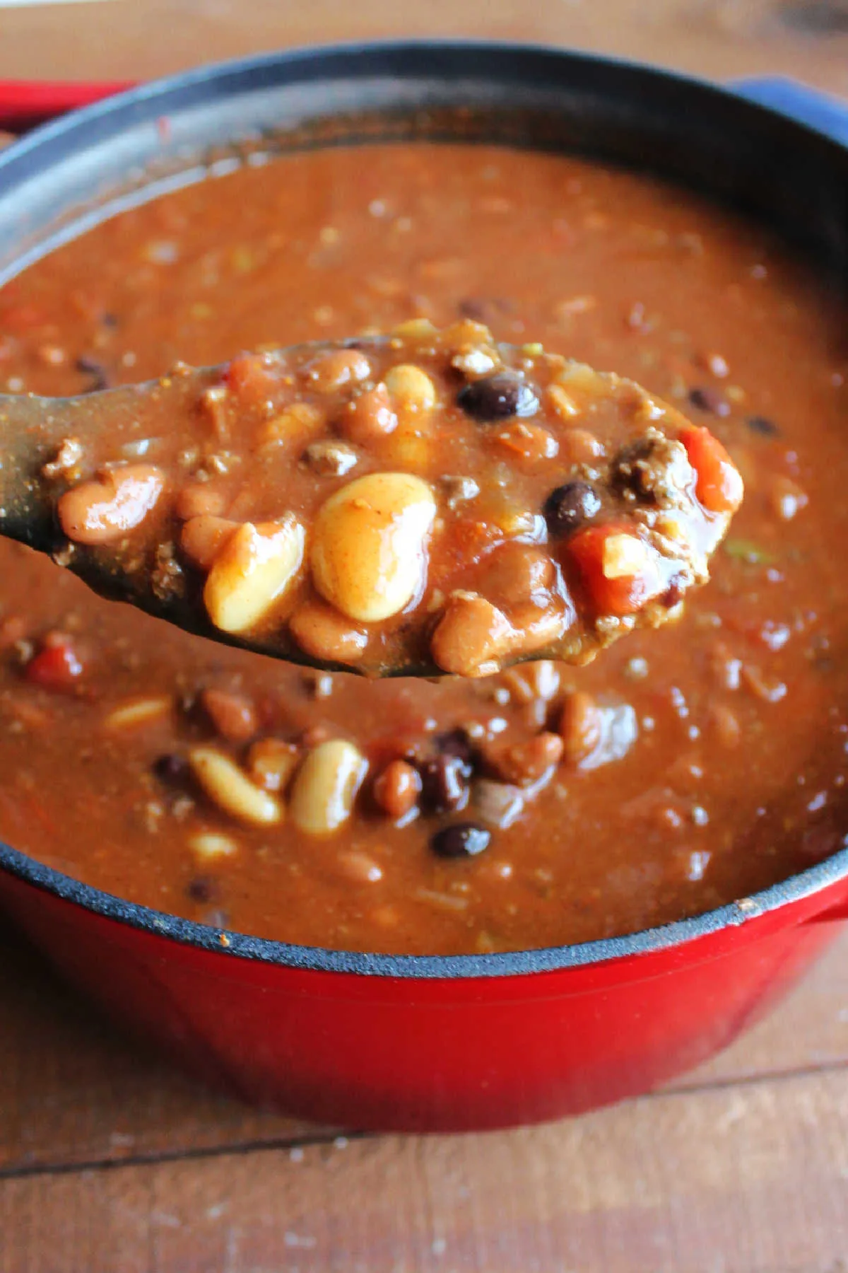 Large serving spoon filled with a heaping scoop of venison chili showing a variety of beans.