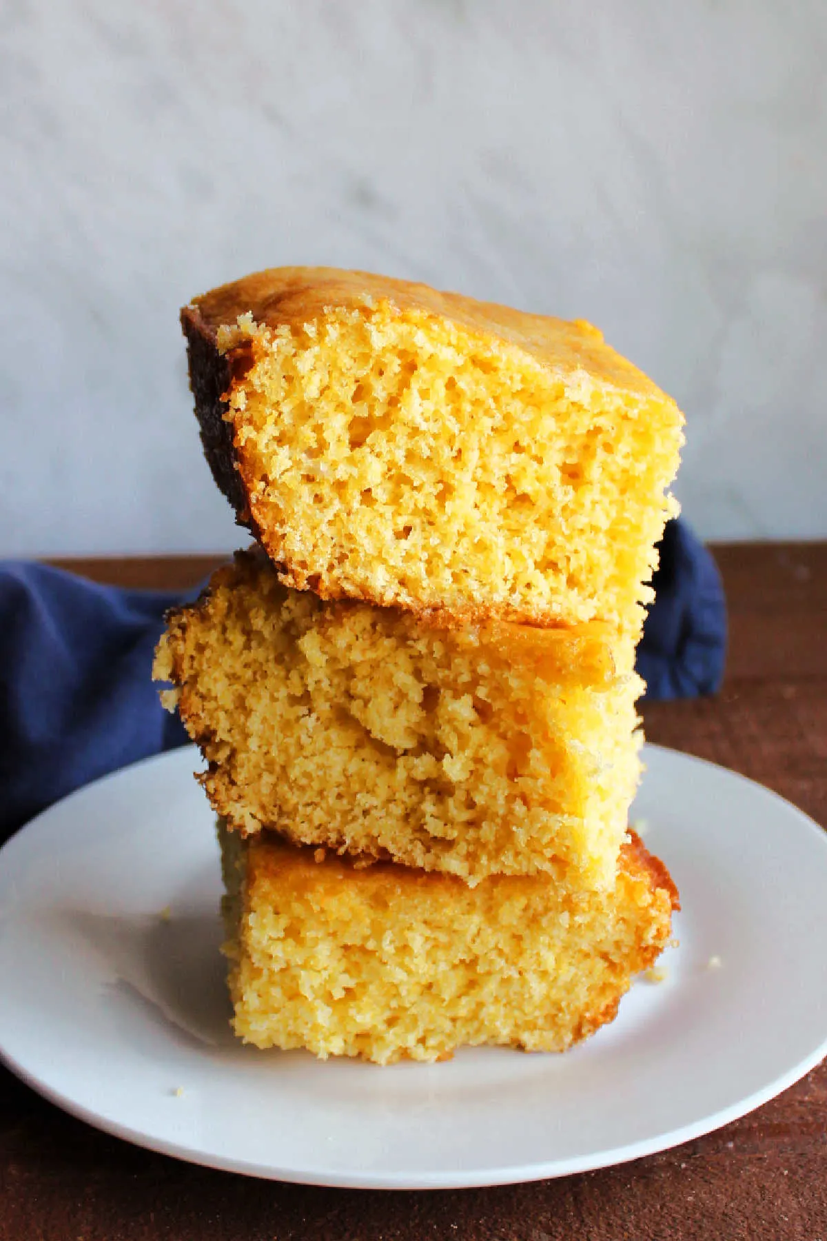 Stack of squares of soft moist yellow cornbread pieces.