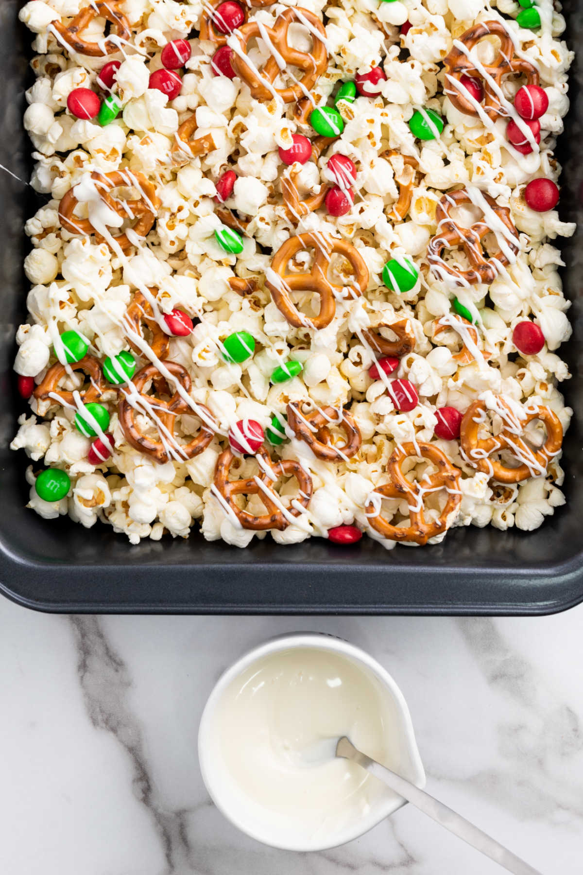 Drizzling melted white chocolate over popcorn, pretzels and candies.