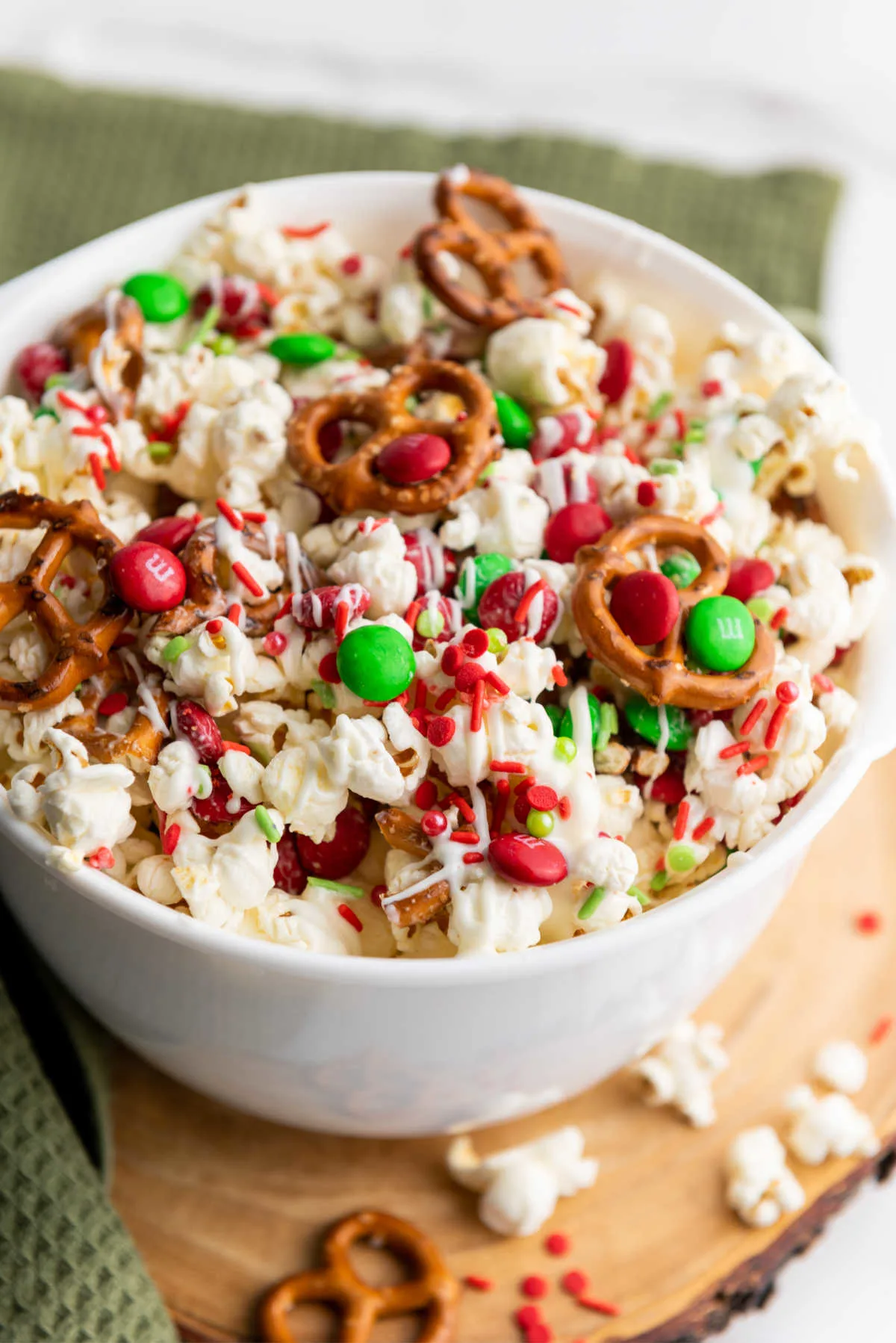 Big white serving bowl filled with sweet and salty Christmas crunch snack mix.