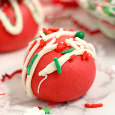 Red Velvet Truffles 2 Close up of smooth red velvet truffles topped with white chocolate drizzle and Christmas sprinkles.