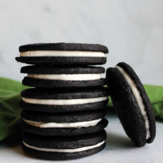 Stack of homemade oreos showing thin dark chocolate cookies and creamy white filling.