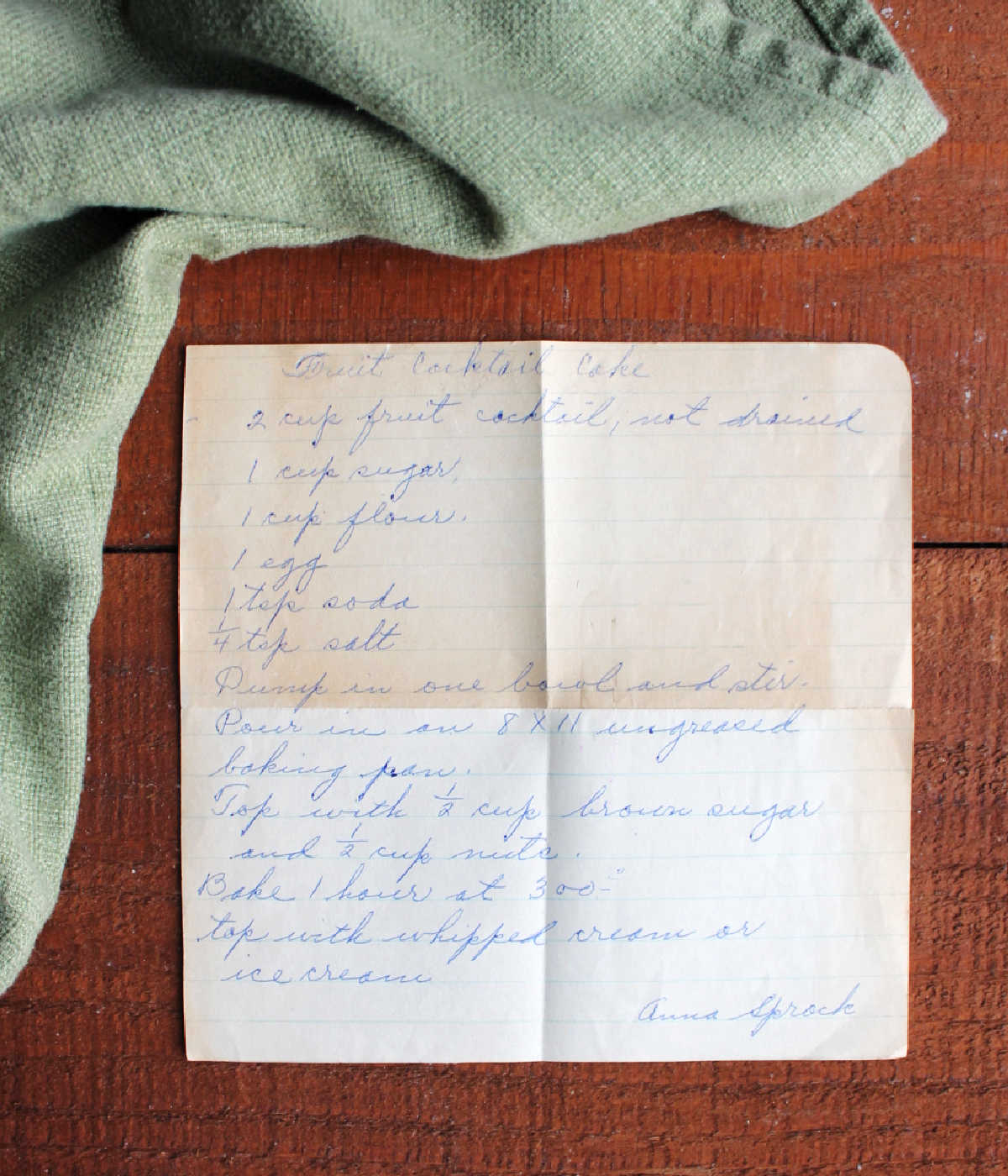 Hand written recipe for fruit cocktail cake on yellowed piece of paper.