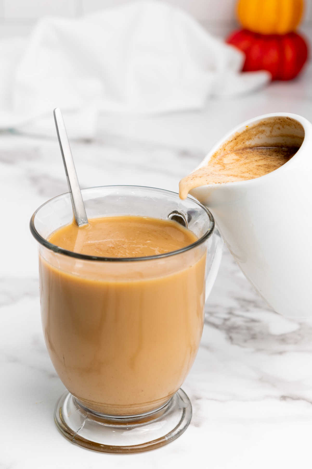 Pouring pumpkin spice creamer into a mug of coffee.