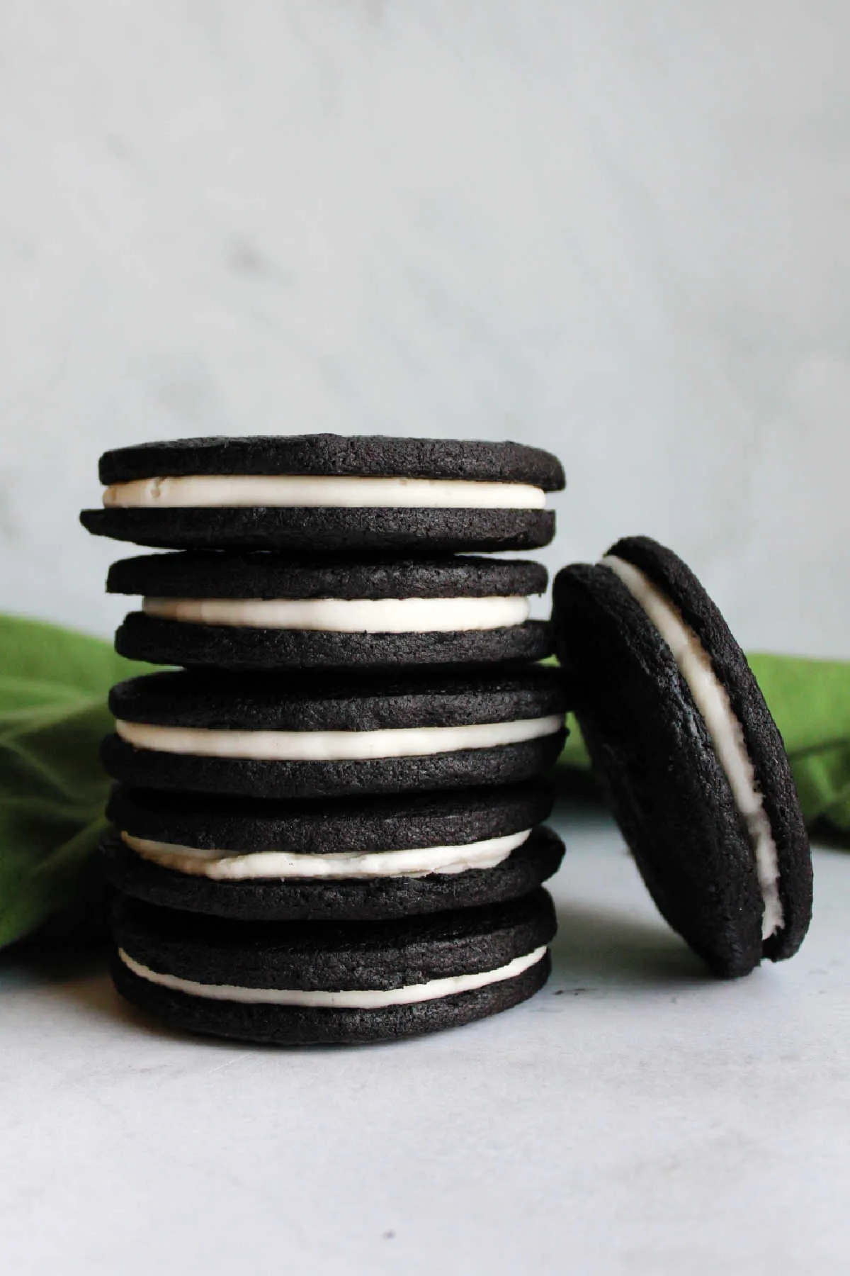 Stack of homemade oreos showing thin dark chocolate cookies and creamy white filling.