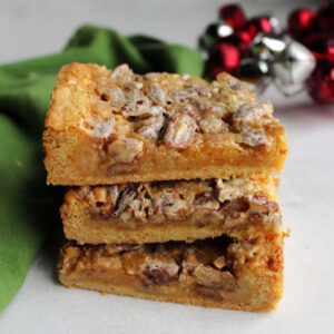 Stack of pecan dream bars with thin cakey crust and gooey pecan topping.