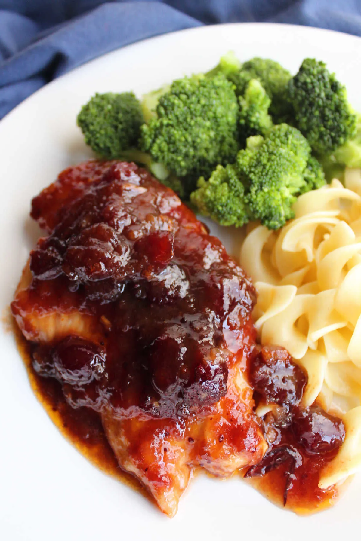 Cranberry chicken breast served with egg noodles and steamed broccoli.