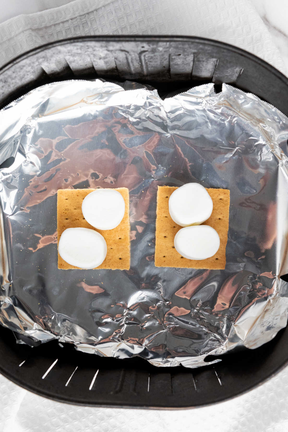 Graham crackers and marshmallows in foil lined air fryer basket.