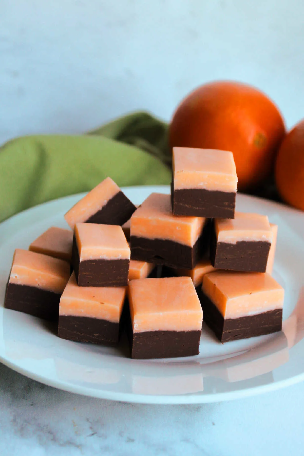 Pieces of chocolate orange fudge on plate with oranges in background.