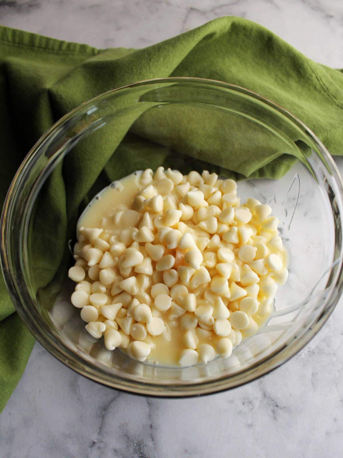 White chocolate chips and condensed milk in a small glass bowl.