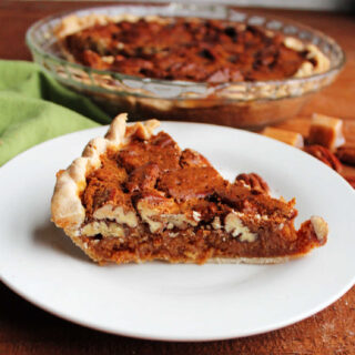 Slice of caramel pecan pie with thick layer of pecans on top and rich caramel layer underneath.
