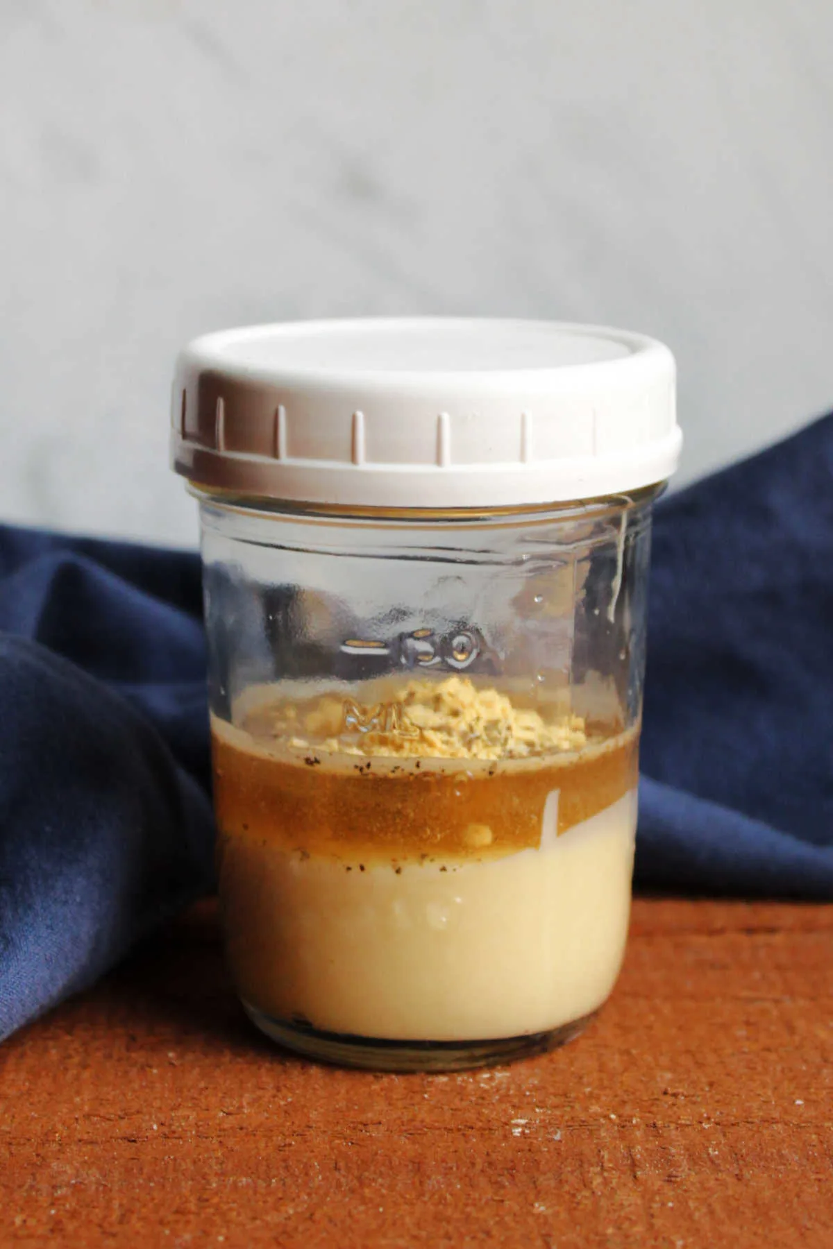 Layers of condensed milk, vinegar and seasonings in jar ready to be mixed into dressing.
