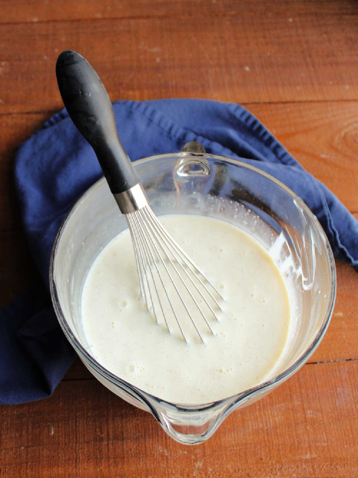 Eggnog ice cream base in glass mixing bowl with a whisk, ready to go in the ice cream maker.