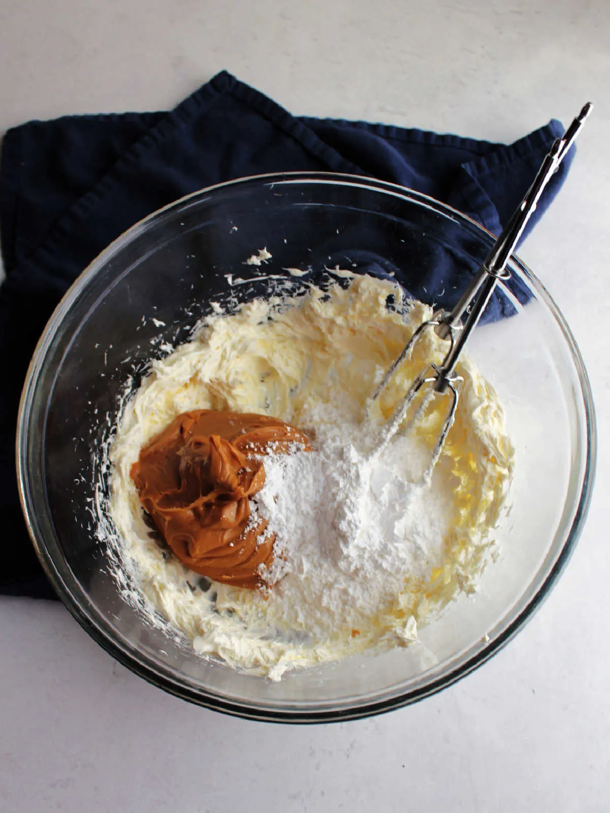Adding peanut butter and powdered sugar to beaten cream cheese.