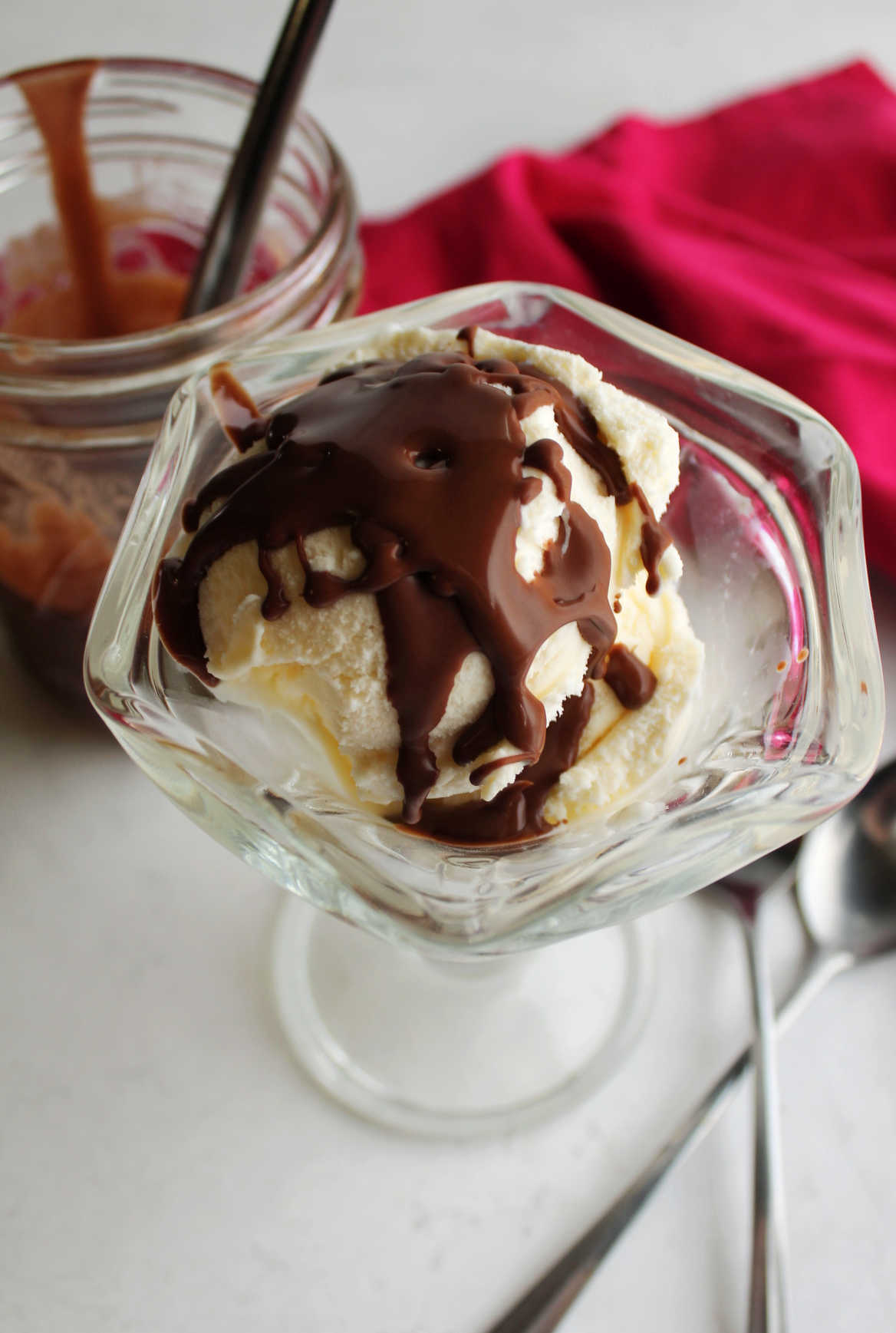 Glass sundae dish filled with vanilla ice cream topped with homemade chocolate magic shell.
