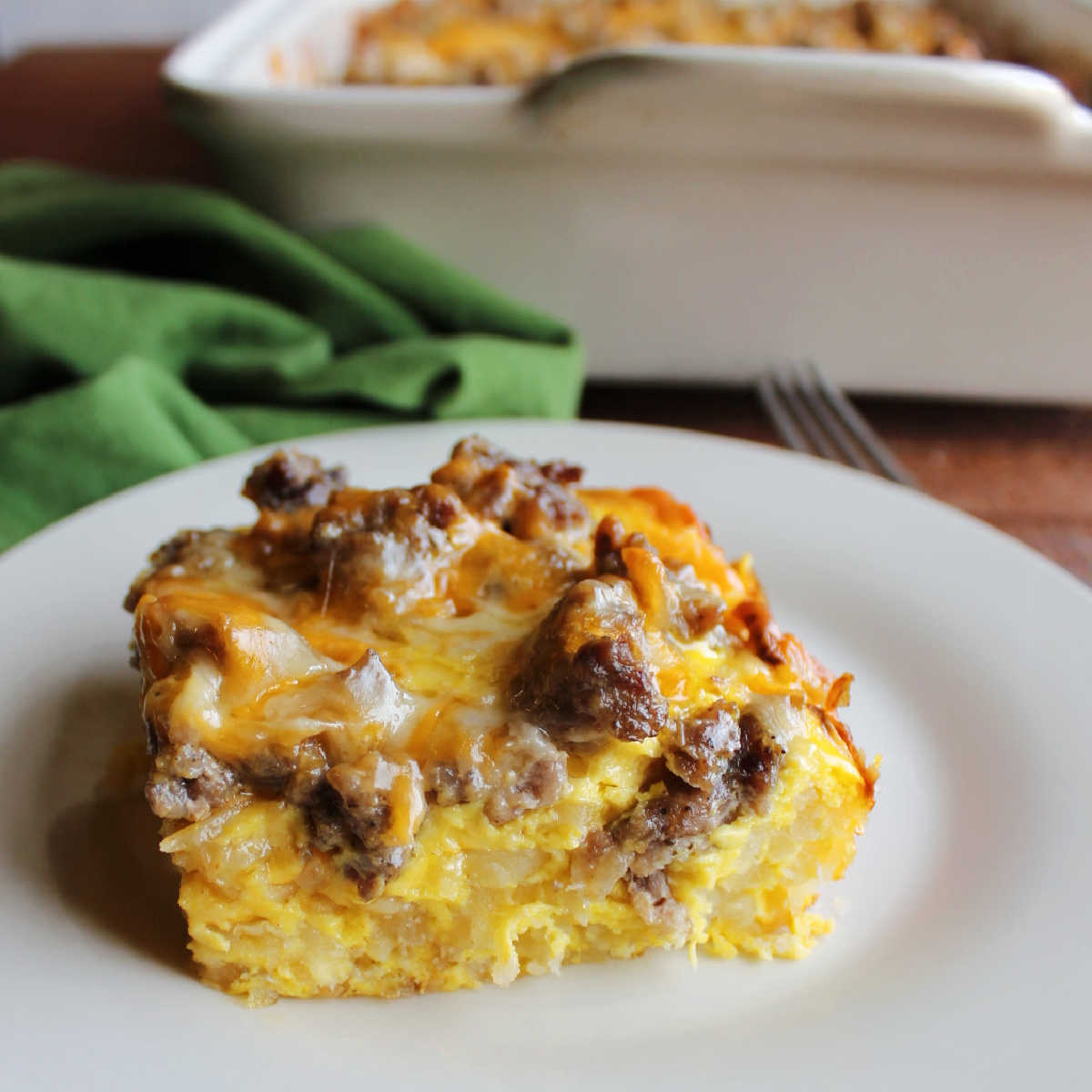 Piece of hashbrown egg casserole with sausage and cheddar cheese ready to be eaten.