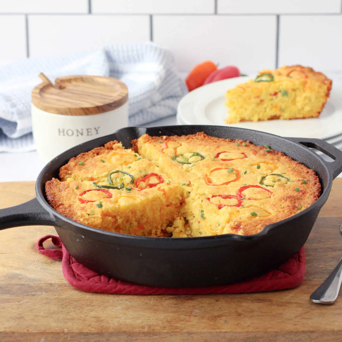 Skillet of loaded cornbread topped with pepper rings and filled with cheese, bacon, and jalapenos.