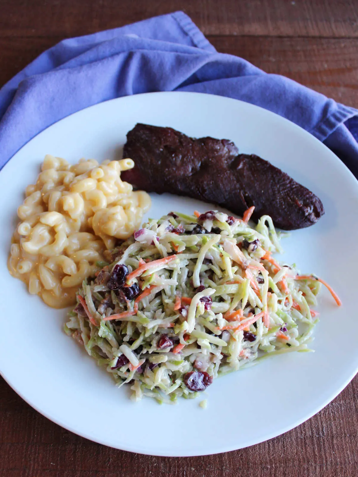 Dinner plate with mac and cheese, broccoli slaw and grilled venison backstrap.