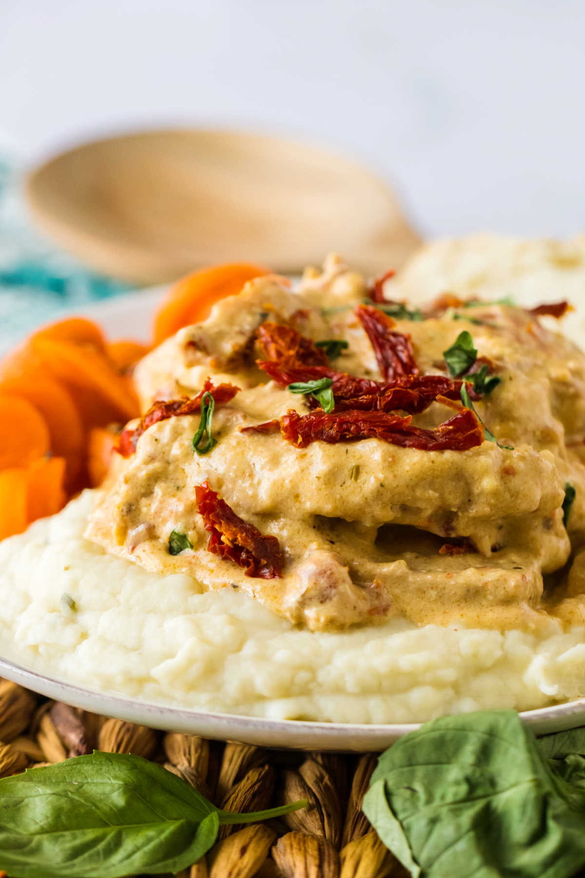 Side view of slow cooker marry me pork chops in creamy sauce on top of a bed of mashed potatoes.